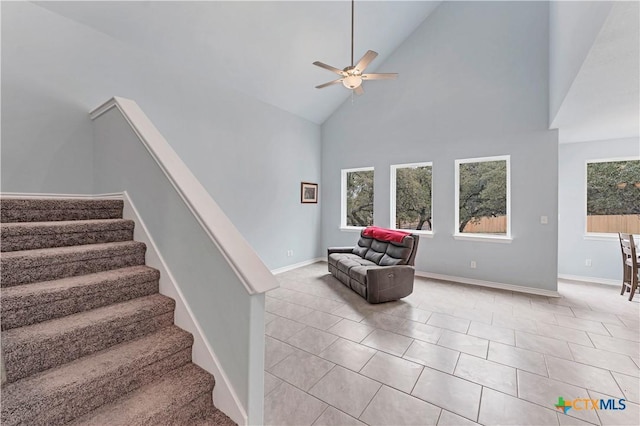 staircase with high vaulted ceiling, tile patterned flooring, ceiling fan, and baseboards