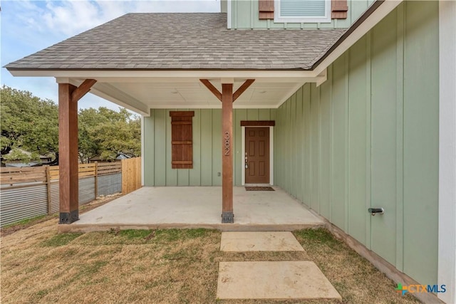 property entrance featuring a shingled roof, board and batten siding, and fence