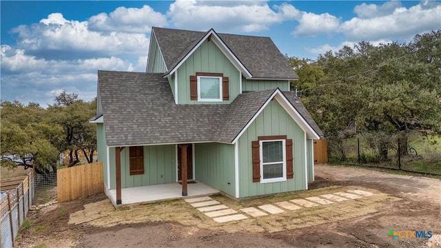 view of front of house with a shingled roof, fence, and a patio