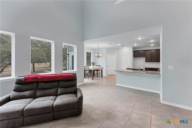 living area featuring baseboards, light tile patterned flooring, and a notable chandelier