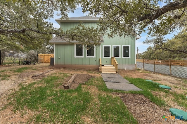 rear view of property with board and batten siding and a fenced backyard