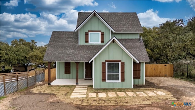 view of front of property with a fenced backyard, board and batten siding, and roof with shingles