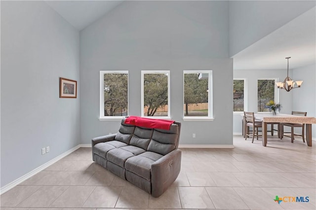 living area with high vaulted ceiling, a notable chandelier, baseboards, and light tile patterned floors