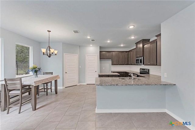 kitchen with dark brown cabinetry, a peninsula, a sink, visible vents, and appliances with stainless steel finishes