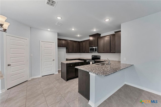 kitchen featuring a sink, visible vents, dark brown cabinets, appliances with stainless steel finishes, and tasteful backsplash