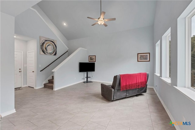 sitting room featuring high vaulted ceiling, a healthy amount of sunlight, baseboards, and stairs