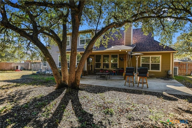 back of house with a patio area, fence, a chimney, and roof with shingles