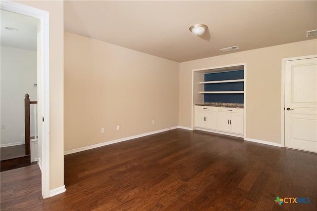 unfurnished living room with visible vents, dark wood finished floors, and baseboards