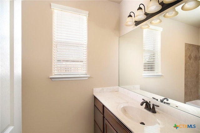 full bath featuring an inviting chandelier, a washtub, and vanity