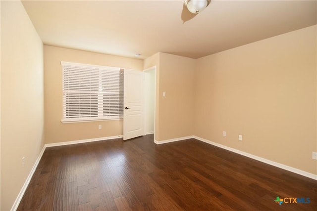 unfurnished room with dark wood-style flooring and baseboards