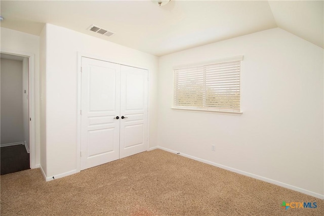 unfurnished bedroom featuring lofted ceiling, carpet flooring, visible vents, baseboards, and a closet