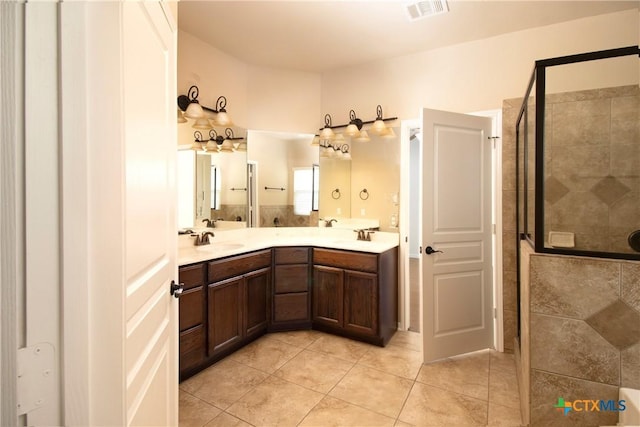 full bathroom featuring double vanity, a stall shower, visible vents, tile patterned floors, and a sink