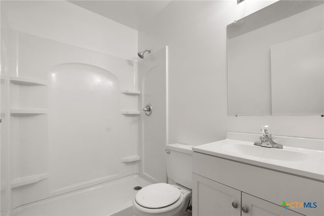 bathroom featuring toilet, a shower, and vanity