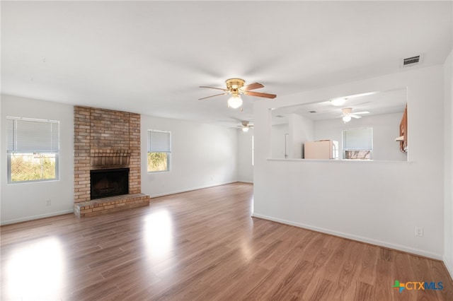 unfurnished living room with ceiling fan, light hardwood / wood-style floors, a healthy amount of sunlight, and a fireplace