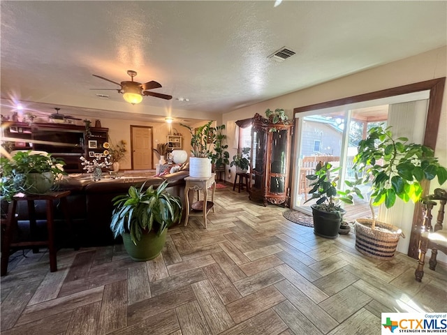 living room featuring a textured ceiling, parquet floors, and ceiling fan