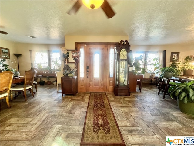 foyer featuring ceiling fan, a textured ceiling, and a healthy amount of sunlight