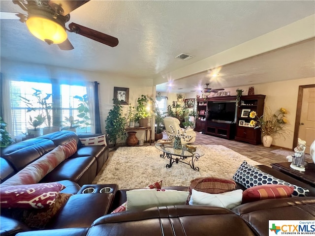 living room with a textured ceiling and ceiling fan