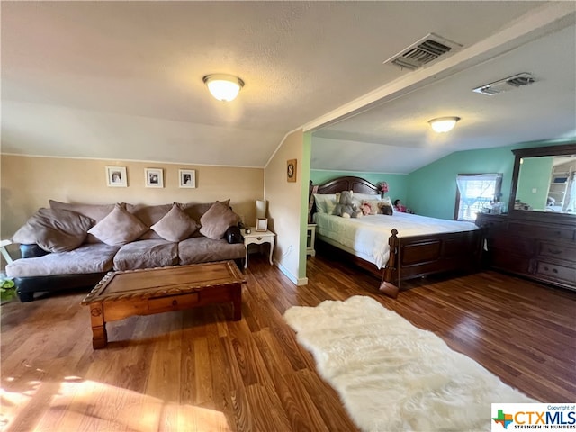 bedroom with dark wood-type flooring, a textured ceiling, and vaulted ceiling