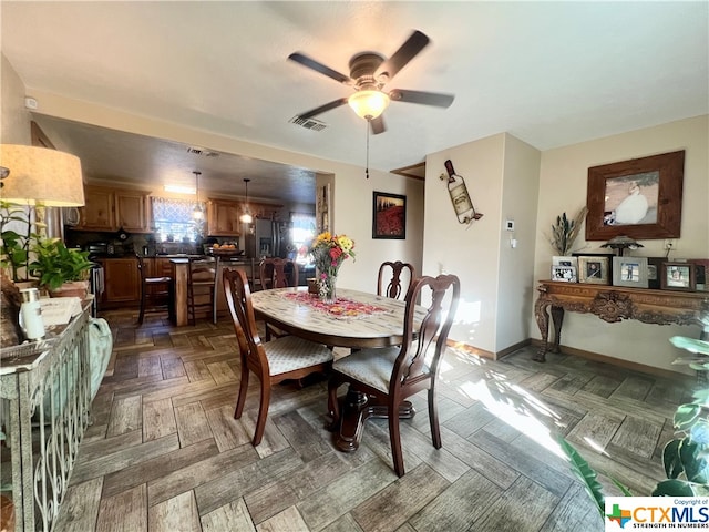 dining space with dark parquet flooring and ceiling fan