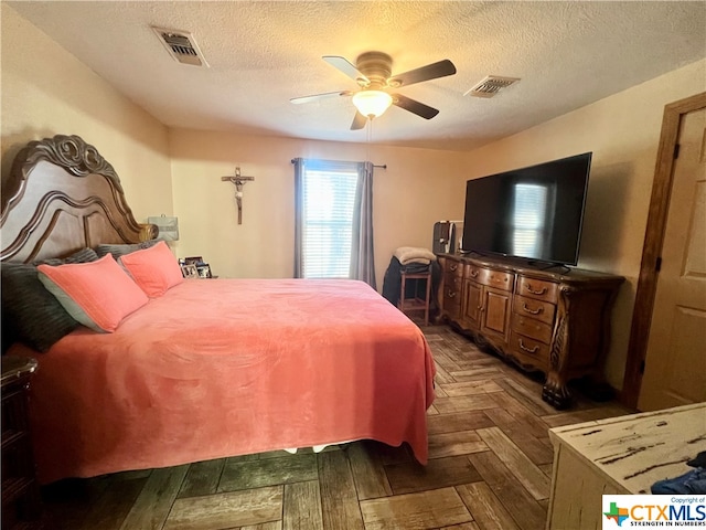 bedroom with dark parquet flooring, a textured ceiling, and ceiling fan