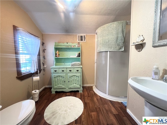 bathroom featuring walk in shower, hardwood / wood-style flooring, a textured ceiling, toilet, and vaulted ceiling