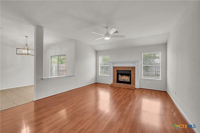 3037 Rain Dance Loop, Harker Heights, TX 76548 - unfurnished living room with wood finished floors, a brick fireplace, ceiling fan, a chandelier, and baseboards
