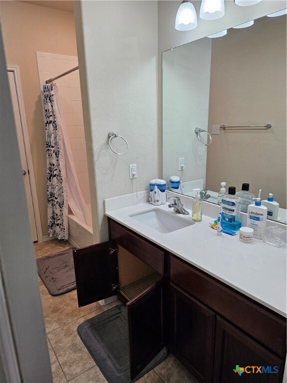 bathroom with vanity, shower / bath combo with shower curtain, and tile patterned flooring