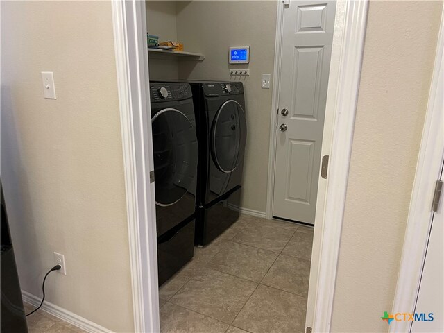 clothes washing area with light tile patterned floors and independent washer and dryer