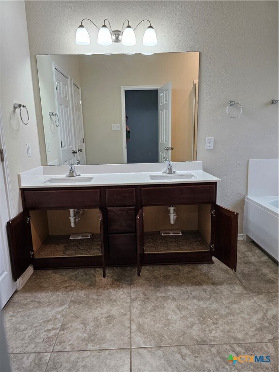 bathroom with tile patterned flooring, vanity, and a tub