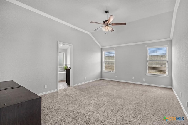 interior space with lofted ceiling, carpet flooring, a ceiling fan, baseboards, and crown molding