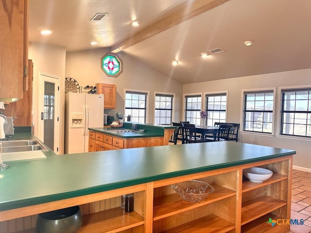 kitchen with white refrigerator with ice dispenser, sink, and vaulted ceiling with beams