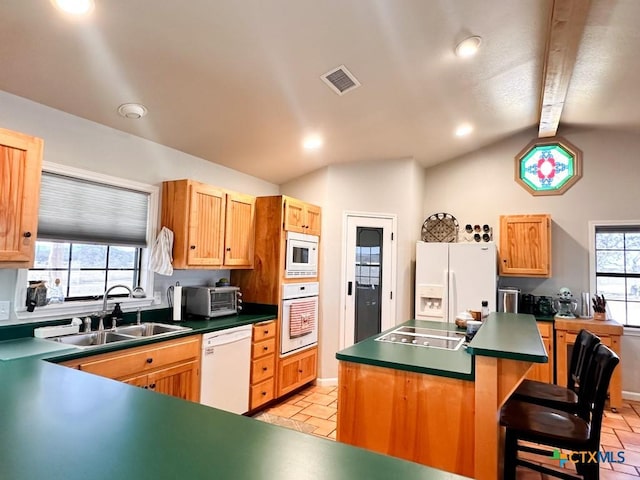 kitchen featuring sink, a breakfast bar area, a center island, plenty of natural light, and white appliances