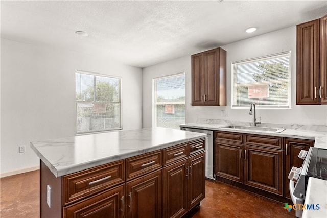 kitchen with sink, a kitchen island, stainless steel dishwasher, and range