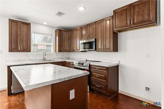 kitchen with appliances with stainless steel finishes, a kitchen island, and sink