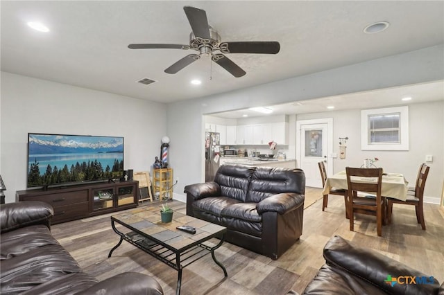 living room with ceiling fan and light hardwood / wood-style flooring