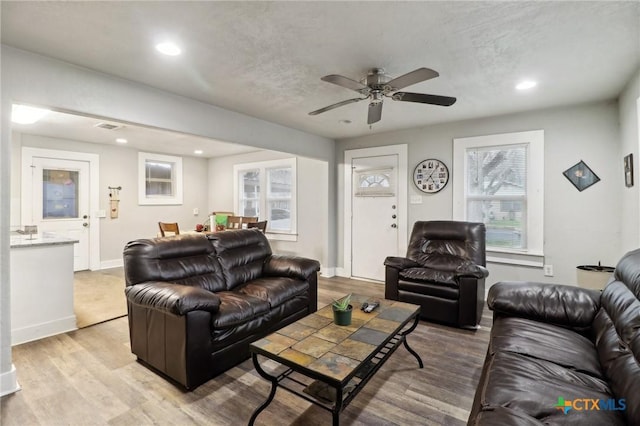 living room featuring ceiling fan, light hardwood / wood-style flooring, and a textured ceiling