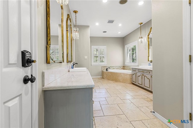 313 Treasure Oaks Rd, Inez, TX 77968 - bathroom featuring a garden tub, two vanities, stone tile floors, a chandelier, and recessed lighting