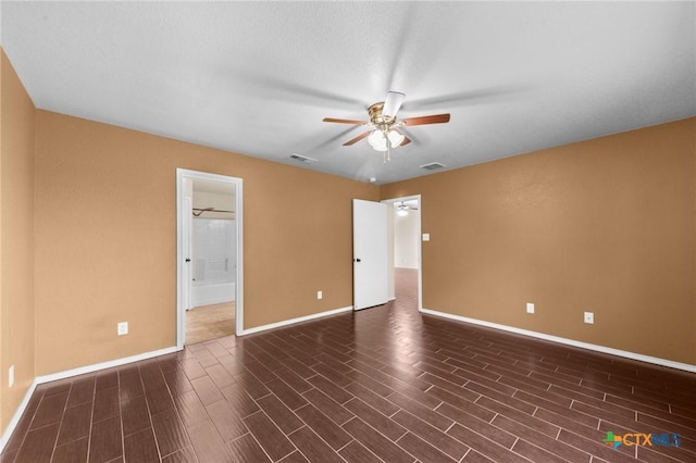 unfurnished room with baseboards, ceiling fan, dark wood finished floors, and visible vents
