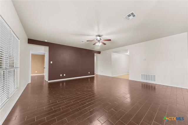 unfurnished room with a ceiling fan, wood finished floors, and visible vents