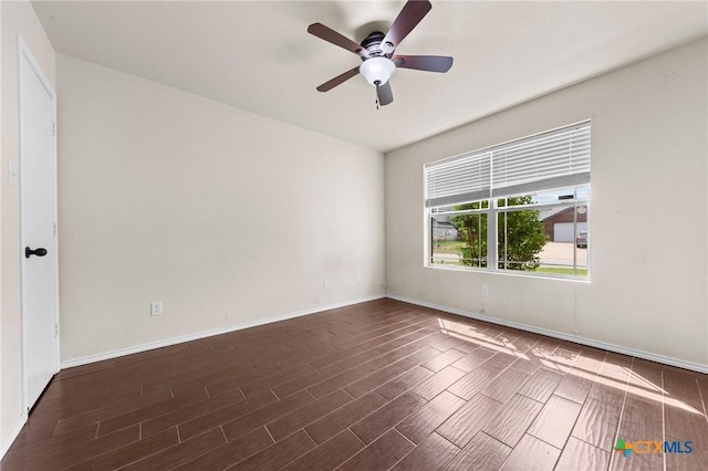 empty room with ceiling fan, baseboards, and dark wood-type flooring