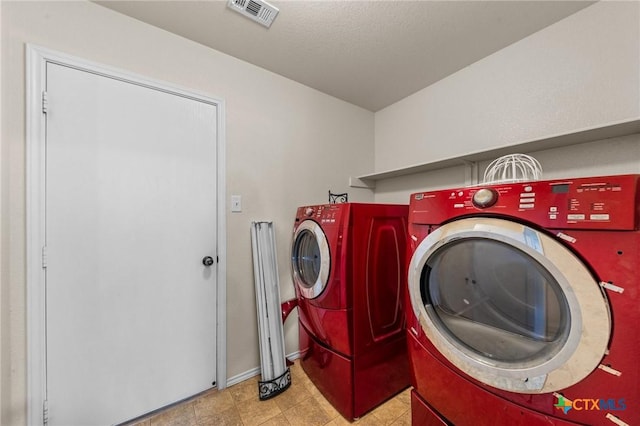 clothes washing area with washing machine and clothes dryer, laundry area, visible vents, and baseboards