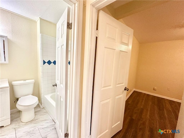 full bathroom featuring vaulted ceiling, tiled shower / bath combo, vanity, toilet, and a textured ceiling