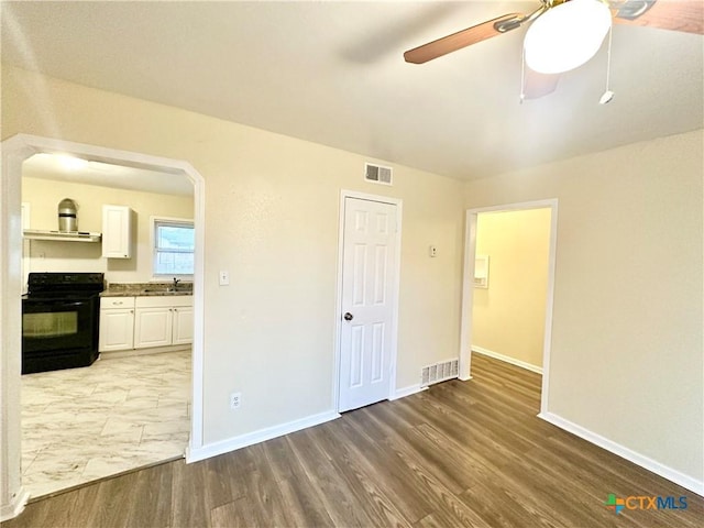 empty room with hardwood / wood-style flooring, sink, and ceiling fan