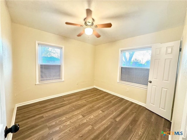 unfurnished room featuring ceiling fan, a healthy amount of sunlight, and dark hardwood / wood-style flooring