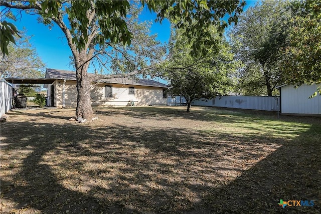 view of yard with an outbuilding, a carport, and fence