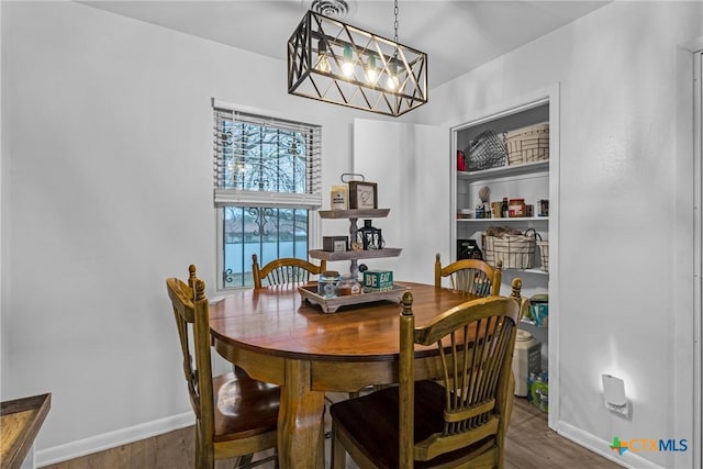 dining room with a notable chandelier, wood finished floors, and baseboards