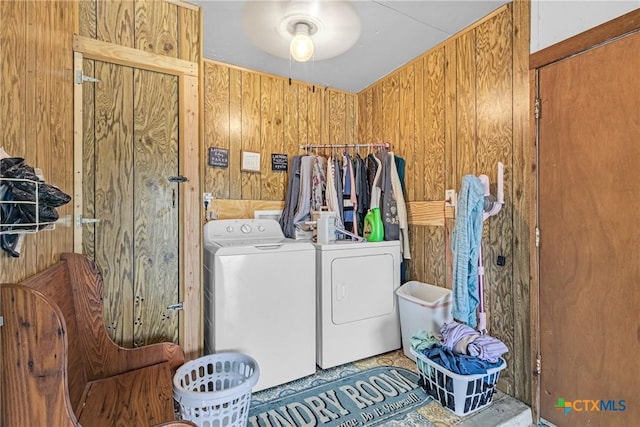 clothes washing area featuring laundry area, washer and clothes dryer, and wood walls