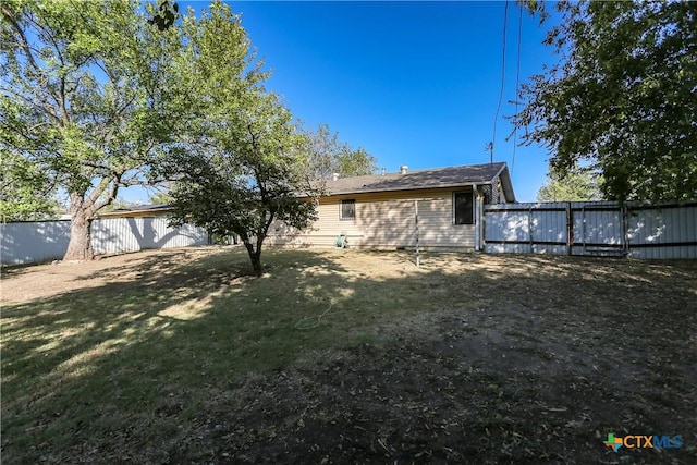 back of house featuring a fenced backyard and a yard