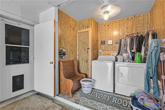 laundry area with laundry area, wooden walls, and washer and clothes dryer