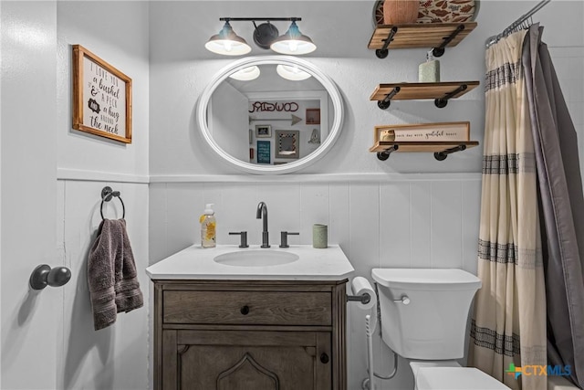 bathroom featuring toilet, a wainscoted wall, a shower with curtain, and vanity